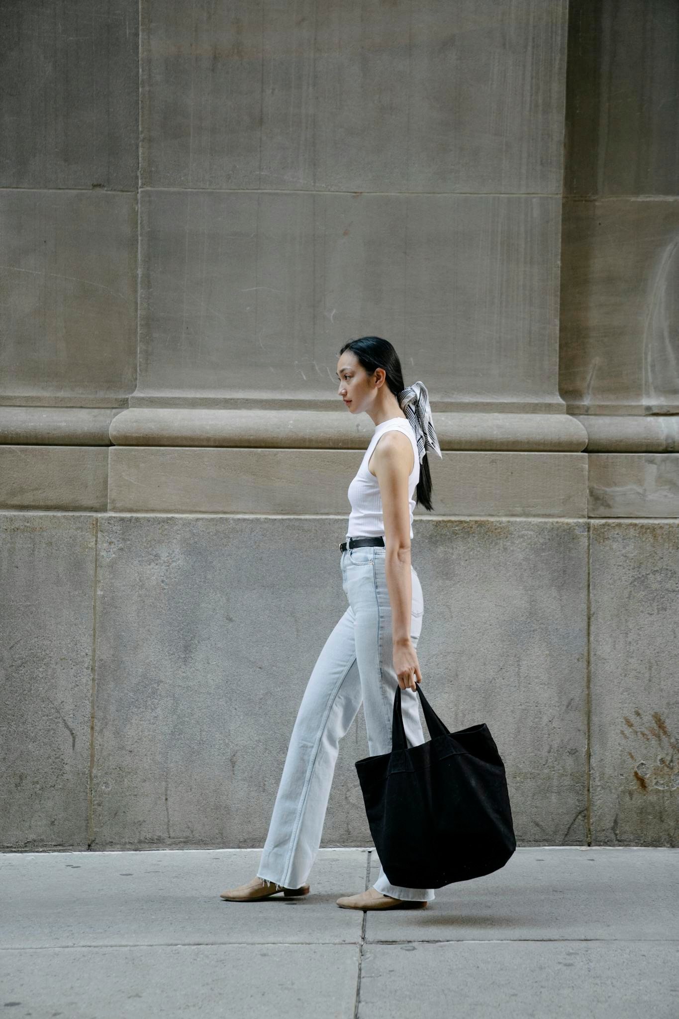 Stylish woman in urban setting carrying eco-friendly tote bag. Modern street fashion.